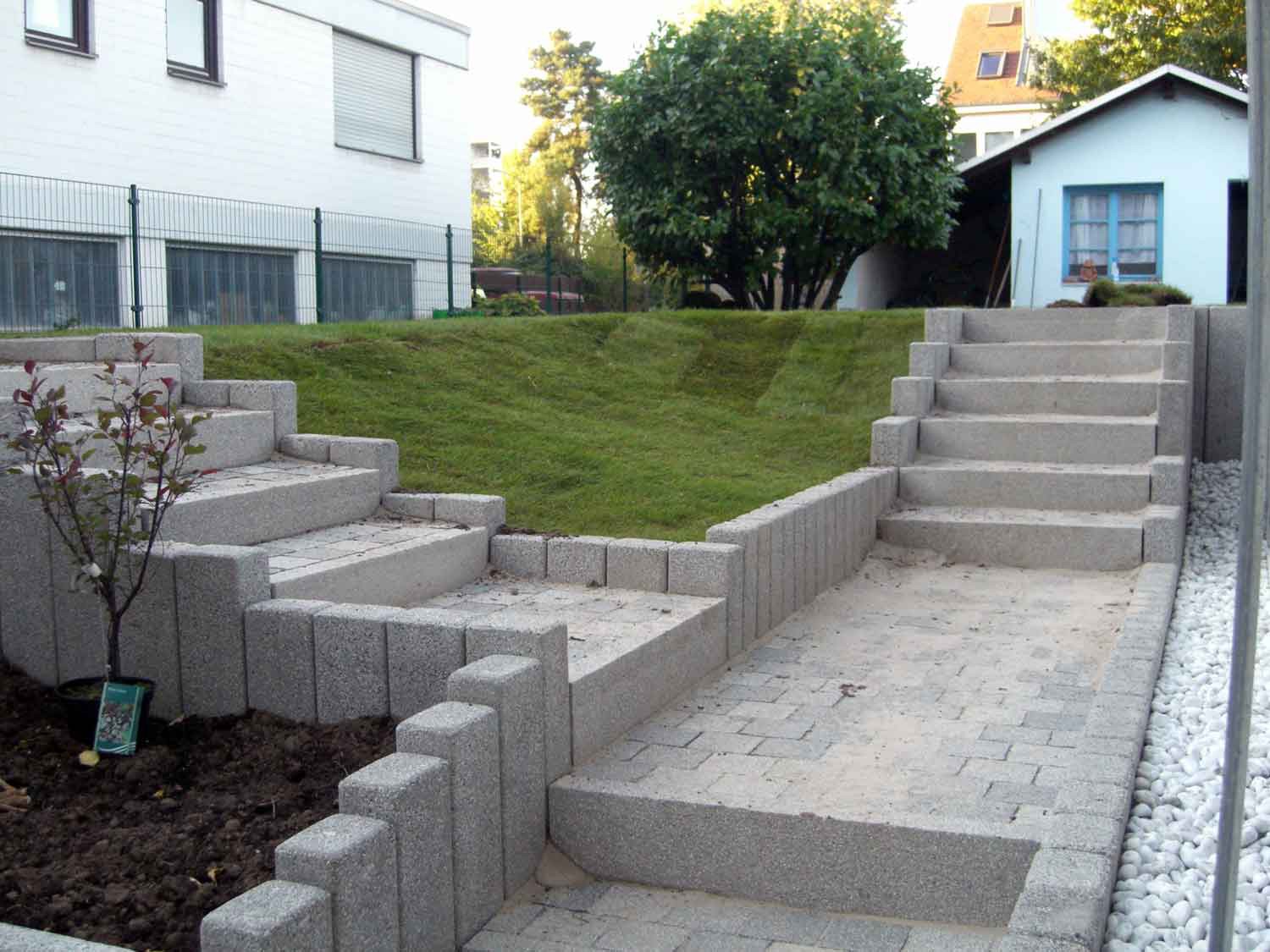 Neu angelegter Garten mit Pflastertreppen, Hangbefestigung und frischem Rollrasen – moderne Außengestaltung mit Höhenanpassung.