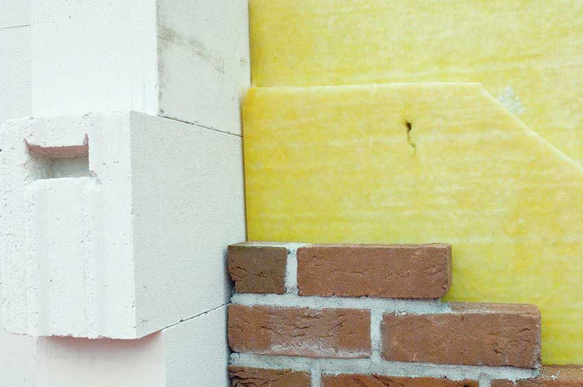 MDS-bautenschutz-bausanierung-frankurt-waermedaemmung-haus-2 Querschnitt durch eine gedämmte Hauswand mit Ziegelverblendung, Dämmstoffschicht und Porenbeton – Beispiel für moderne Wärmedämmung.